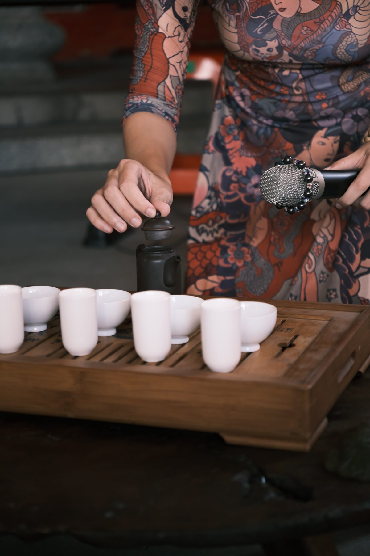 Hands brewing tea beside a microphone during the Prayer of Tea performance
